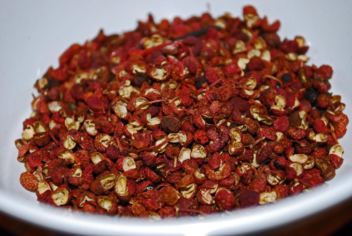 A large number of spicy Sichuan peppercorns in a white bowl