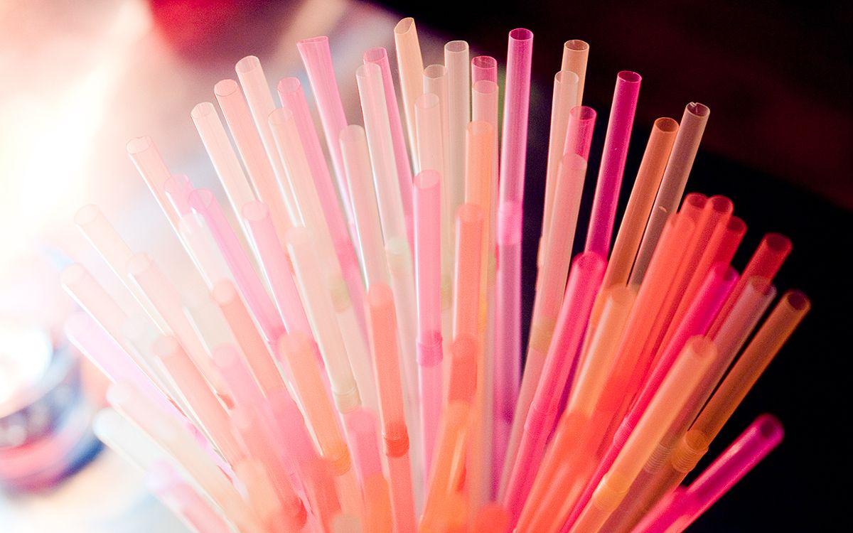 A bunch of straws, mostly pink, grouped together standing upright
