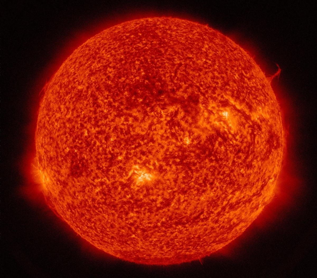 The sun with a dark orange light and a large single solar plume on the right side