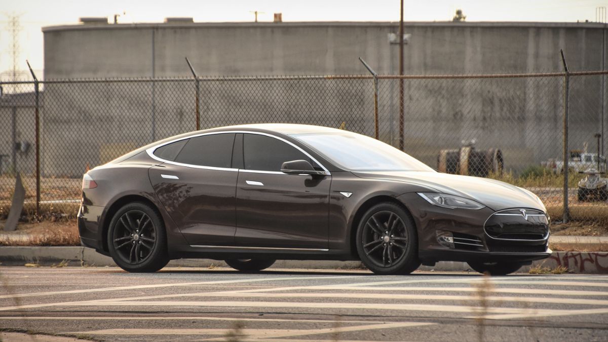A dark Tesla car sits in a parking lot