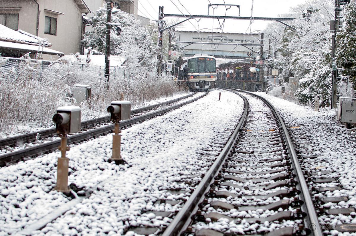 Two lines of tracks with modern trains on them and a light covering of snow