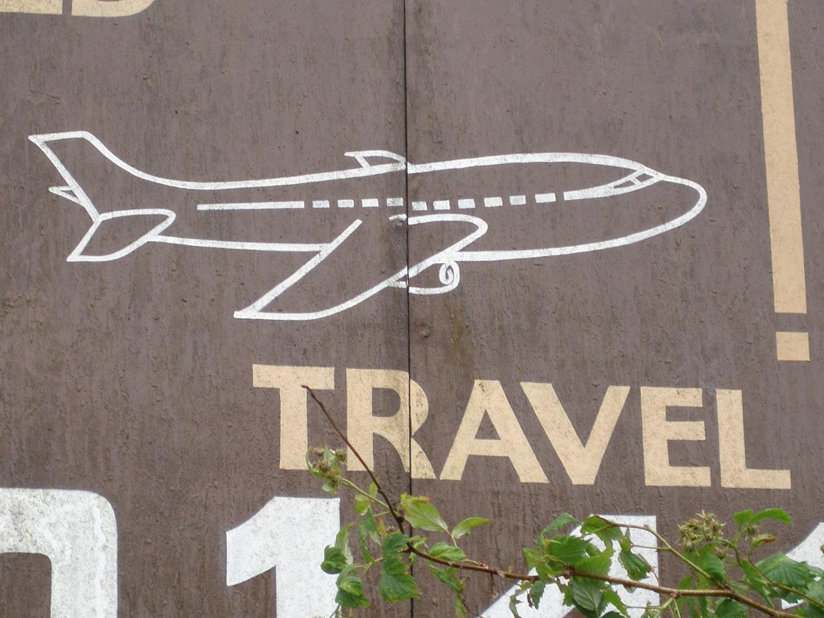 A simple drawing of an airplane on a blacktop with the word "travel" underneath