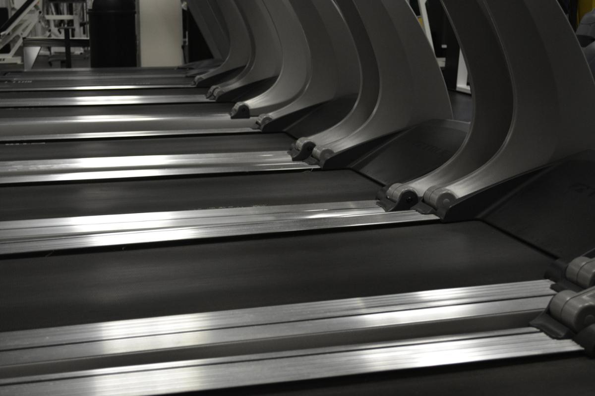 A line of empty treadmills standing next to each other, in black and white