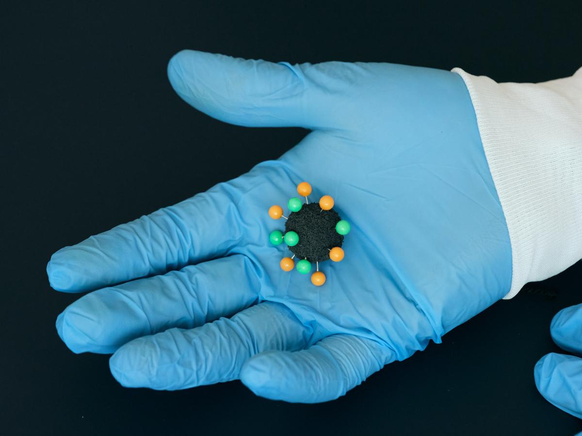 A model of a virus molecule held in a gloved hand