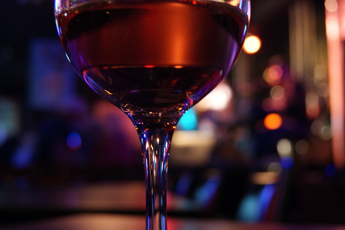 A closeup of a wineglass with neon lights in the background