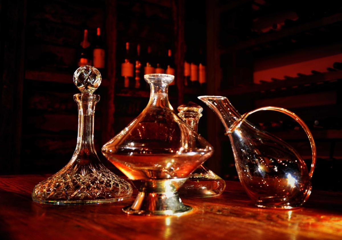 A wide display of various wine decanters in different shapes on a wooden bar