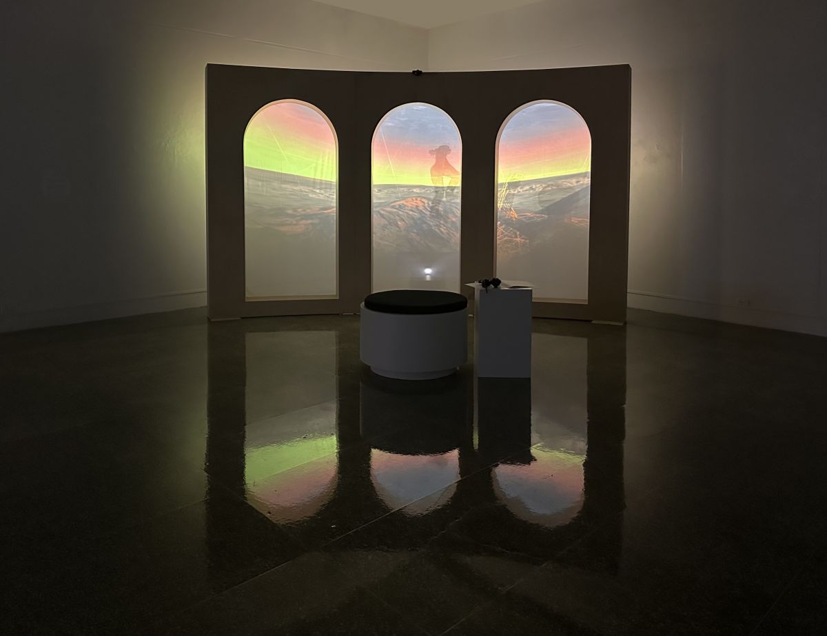 carry:root at the Grunwald Gallery: 3 arches with screens and a projected landscape; in the foreground, a bench with a set of headphones