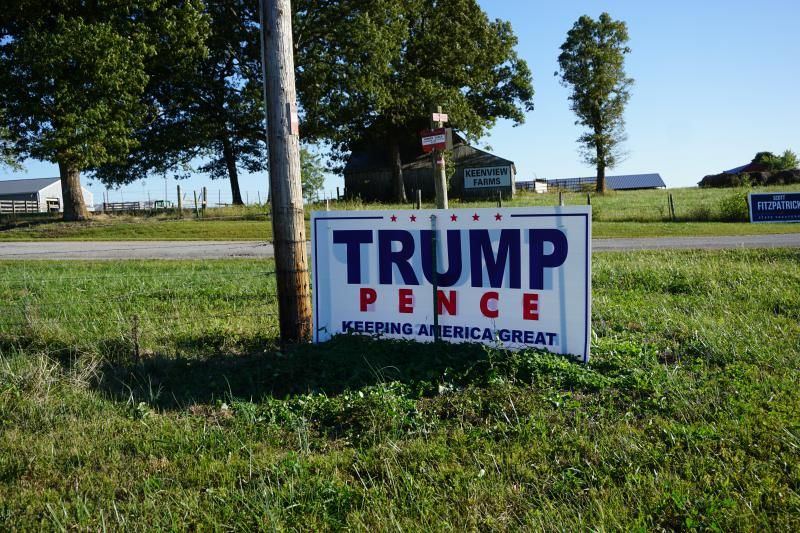 A large Trump/Pence sign on a rural road with barns in the background.