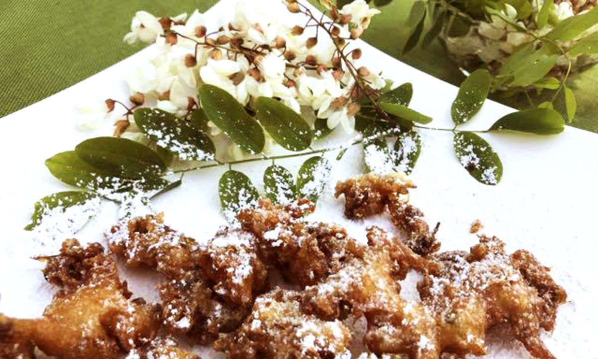 fried dough with powdered sugar sprinkle on a white plate with white flowers on a green table cloth