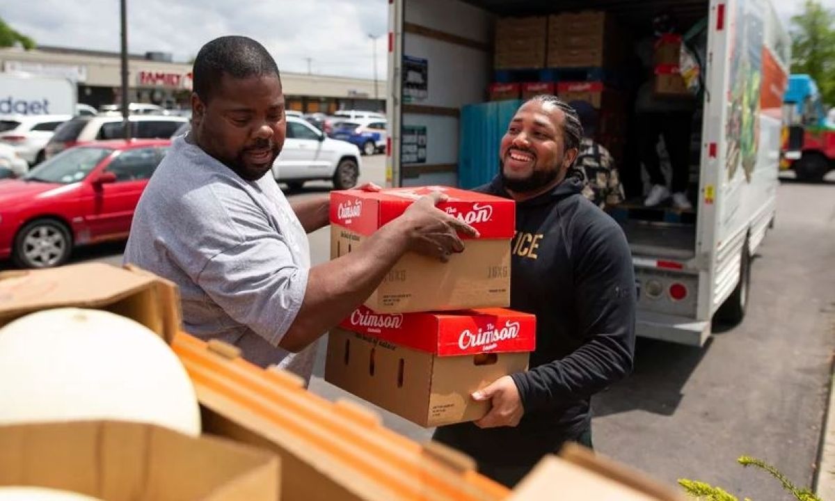 Two guys moving boxes from a truck in a parking lot