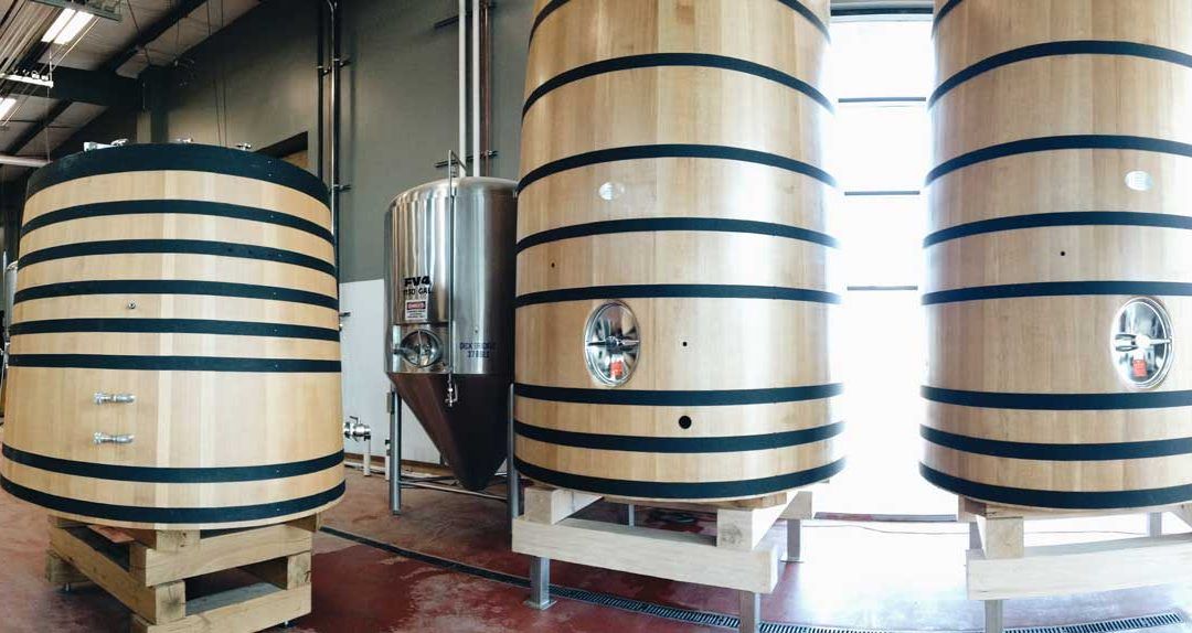 Three tall wooden vats in a large room