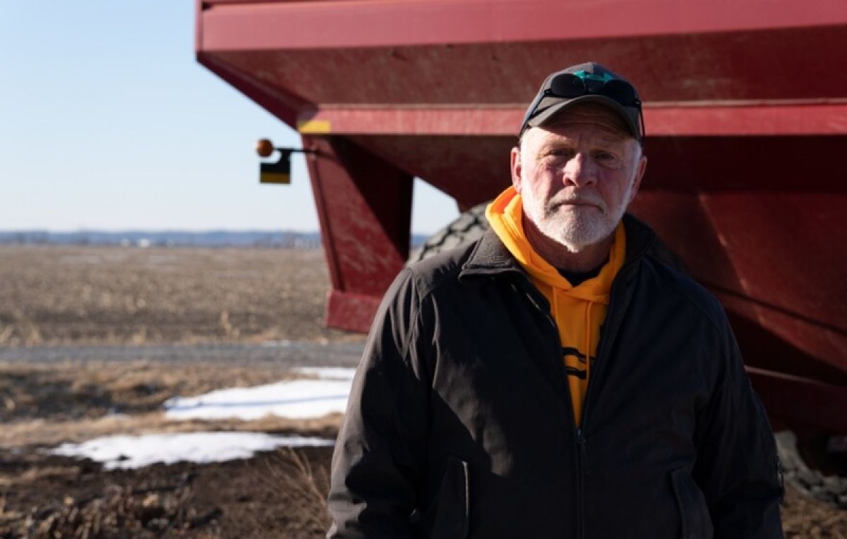 Farmer in front of a field and machinery