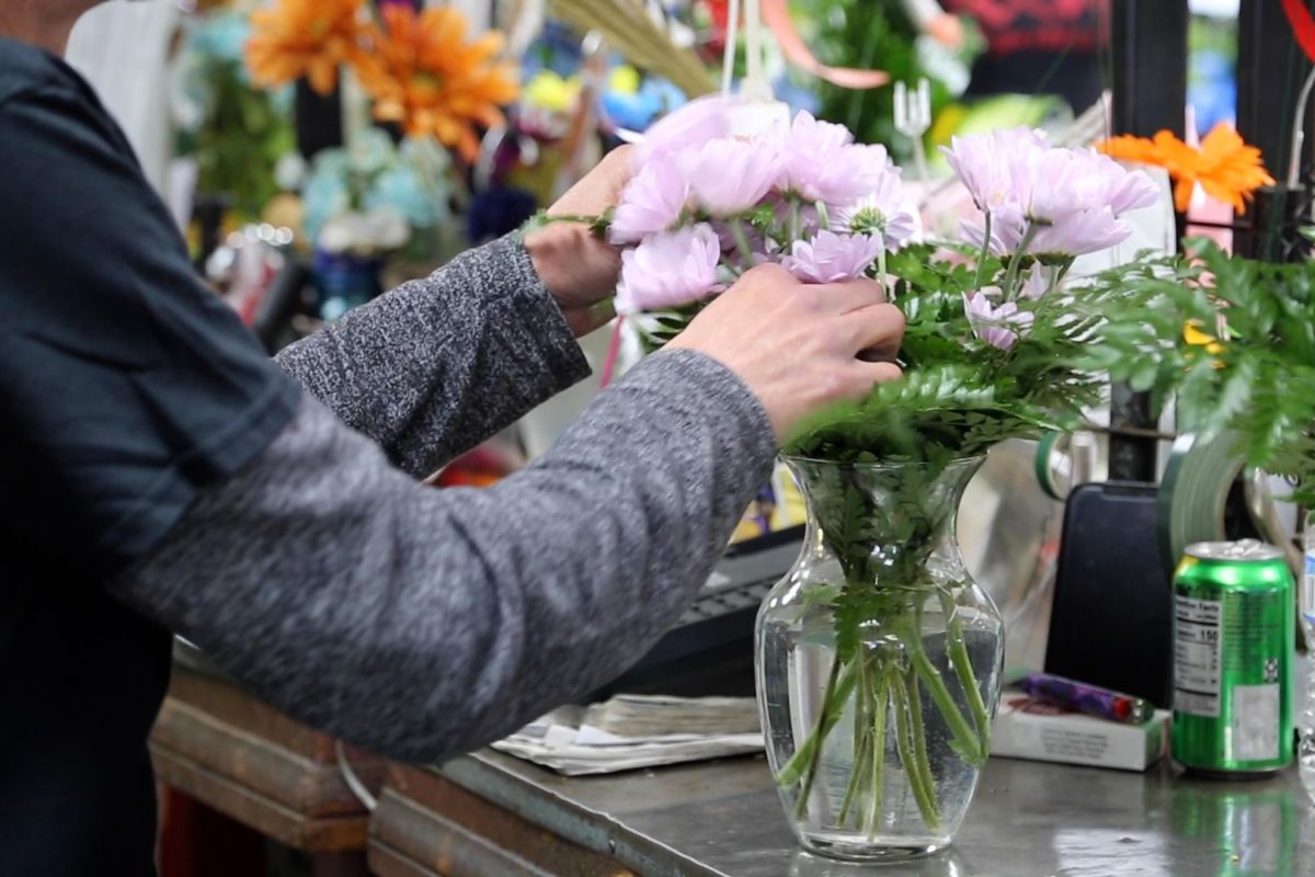 A worker at Mary M's arranges a vase of flowers for Valentine's Day.