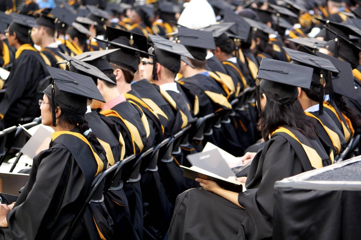 Graduates sit in a row at a graduation.