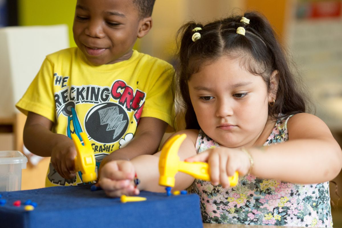 two children play with a carpenter's toy playset