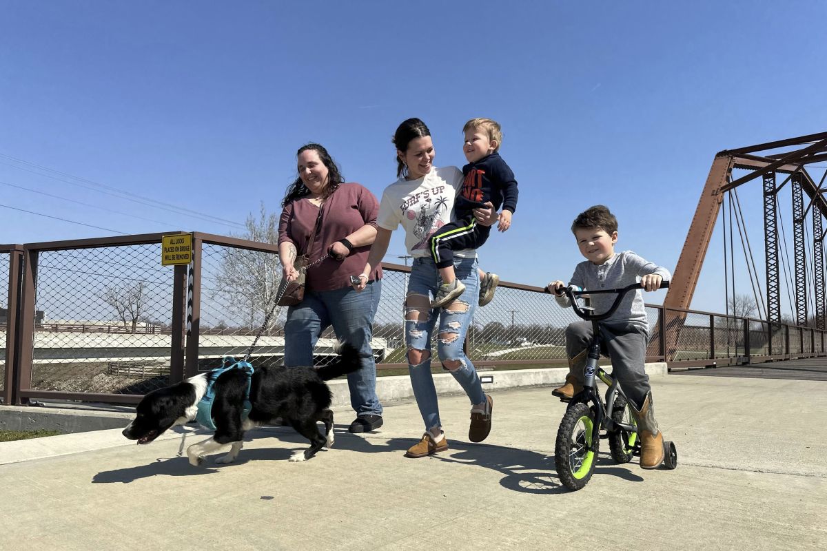From left; Emerson Howard and dog Dixie enjoy a walk along with Destiny Porter and her children, 2-year old Merrick Mercer and 4-year old Maxton Mercer at the Kitselman bridge connecting the Cardinal and White River Greenway trails in Muncie 3/13/24