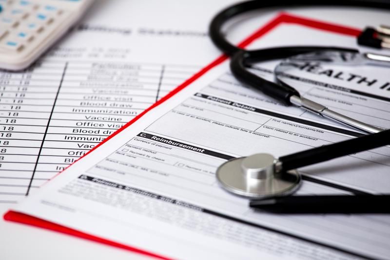 A stock image of healthcare and insurance-related documents under a stethoscope.