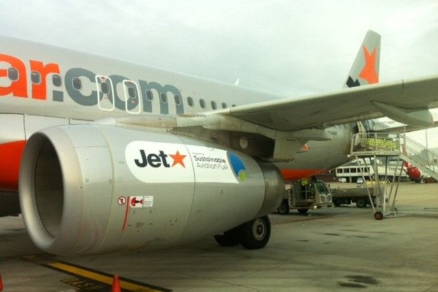 Australian Jetstar Airways has its first flight using biofuels in 2012 using half recycled cooking oil and half traditional jet fuel. A jet sits on a tarmack and on its engine is a sticker with the Jetstar logo and 'sustainable aviation fuel' on it.