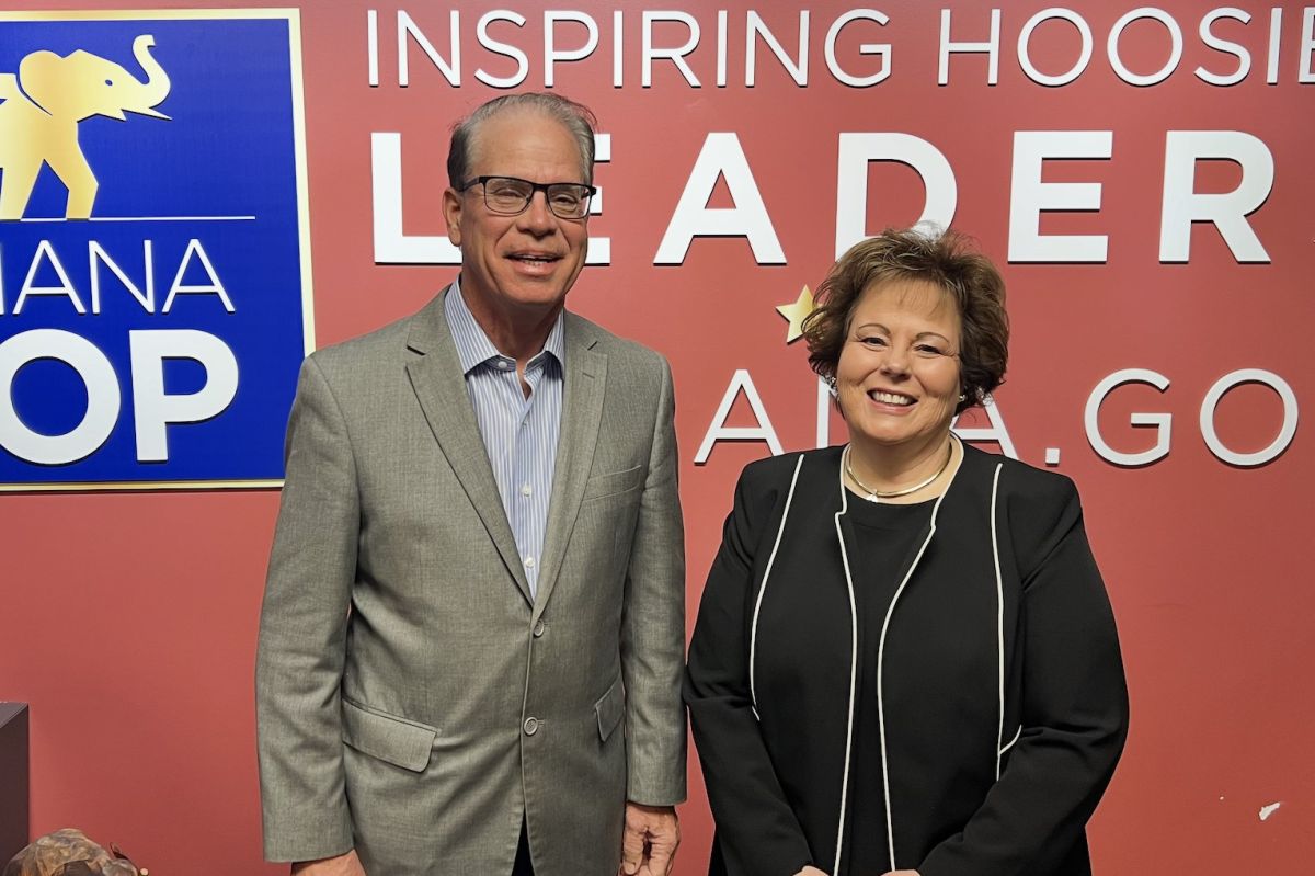 Mike Braun stands next to Lana Keesling. Braun is a White man, balding with dark hair. He is wearing glasses and a tan suit jacket. Keesling is a White woman with dark hair. She is wearing a black suit.