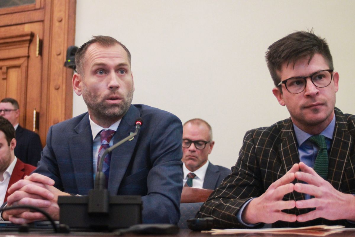 Brock Herr and Mark Wasky sit at a desk, with a microphone between them. Herr is a White man, balding with dark, graying hair and beard. Wasky is a White man with dark hair and wearing glasses.