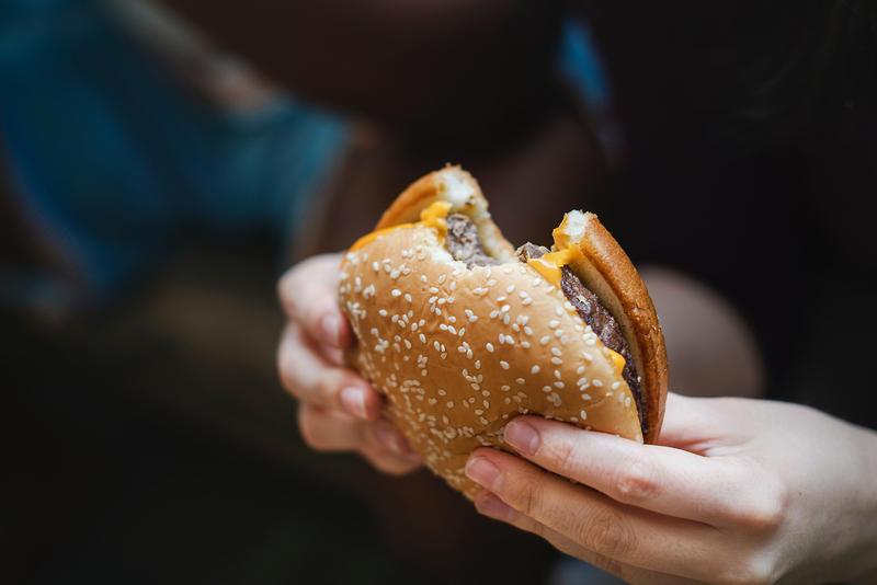 A stock photo of a person holding a cheeseburger.