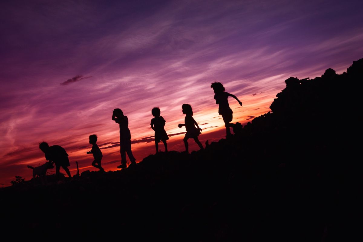 silhouette of children running on hill