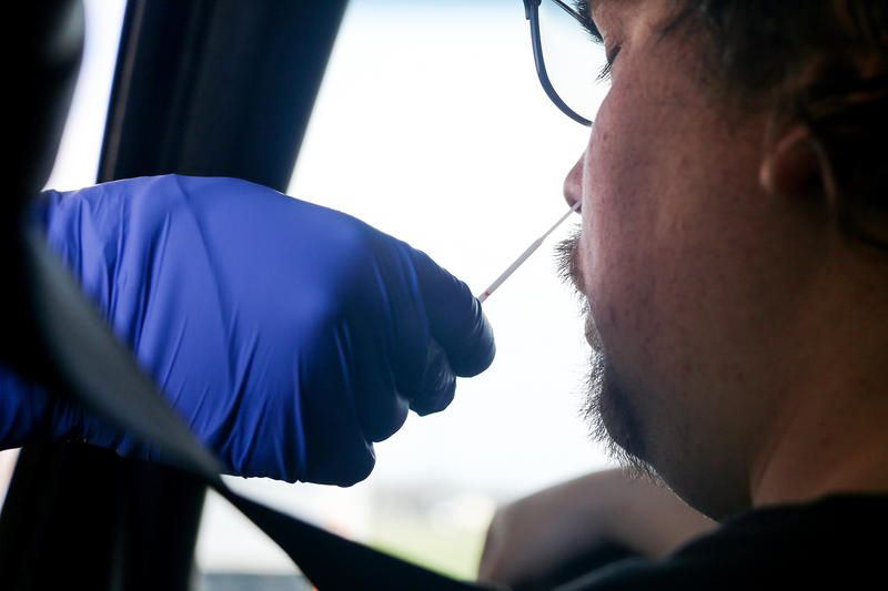A person receiving a nasal swab test for COVID-19 or coronavirus in their car.