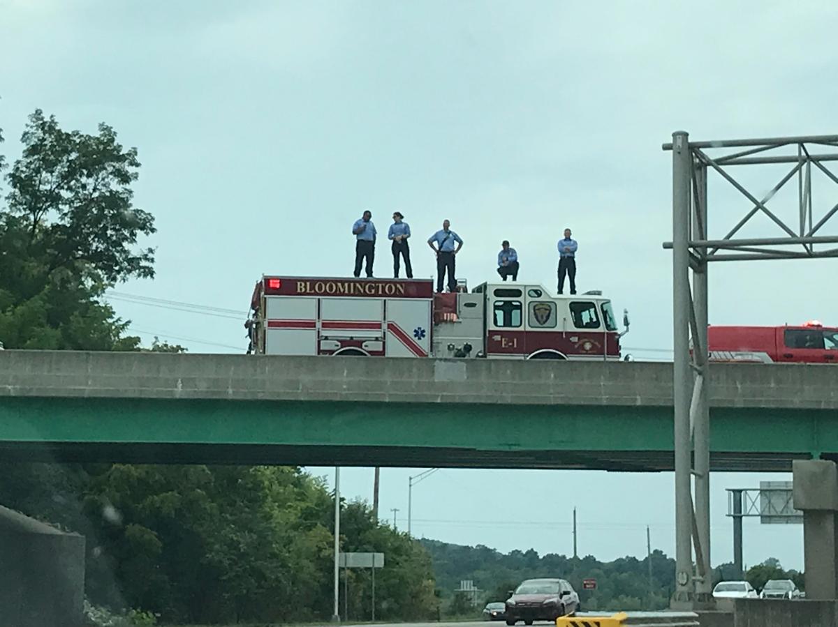 Bloomington fire fighters stand on an overpass of Ind. 45/46 Wednesday for the funeral procession of Owen County EMT Brandon Staley. 
