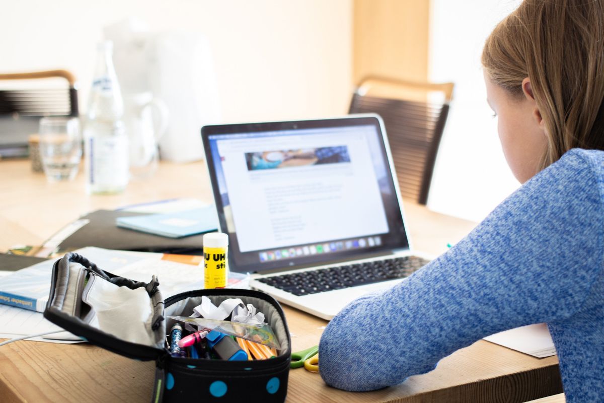 A student sits in front of a laptop at their home.