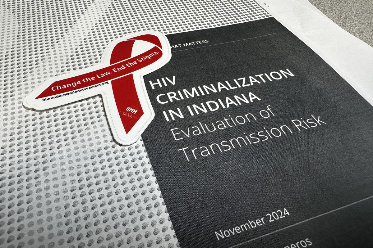 A sticker in the shape of a red ribbon that reads, "Change the Law. End the Stigma." on top of the front page of a report that reads "HIV Criminalization in Indiana: Evaluation of Transmission Risk."