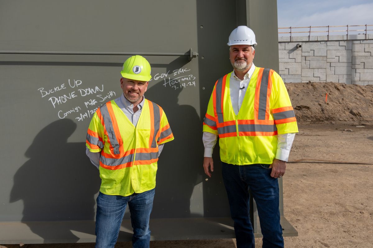 INDOT Commissioner Mike Smith (left) and Gov. Eric Holcomb (right) stand next to their signatures on one of the steel girders to be installed at the I-69/I-465 interchange. 