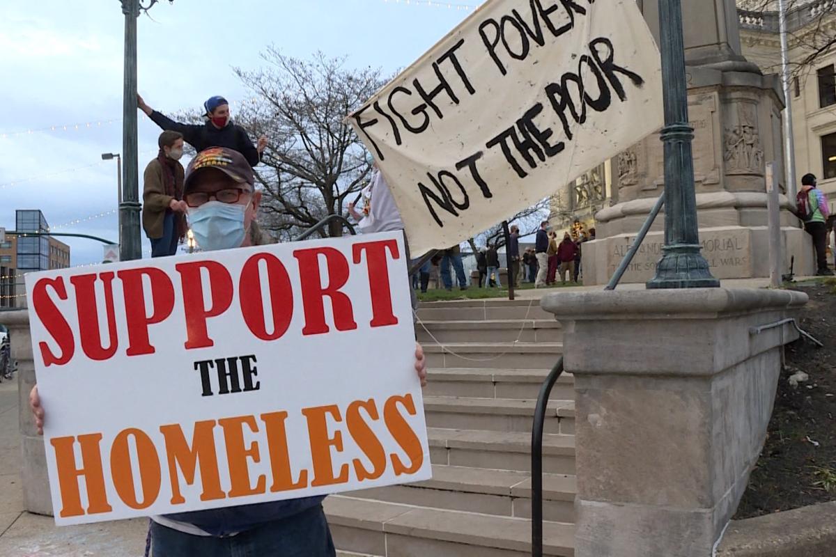 Local residents holding up signs before a rally on homelessness in Bloomington.