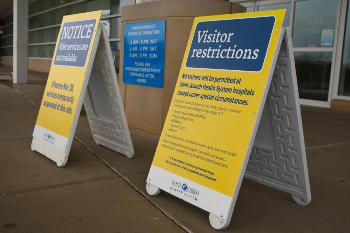 Signs showing visitor restrictions due to covid-19 outside a hospital.