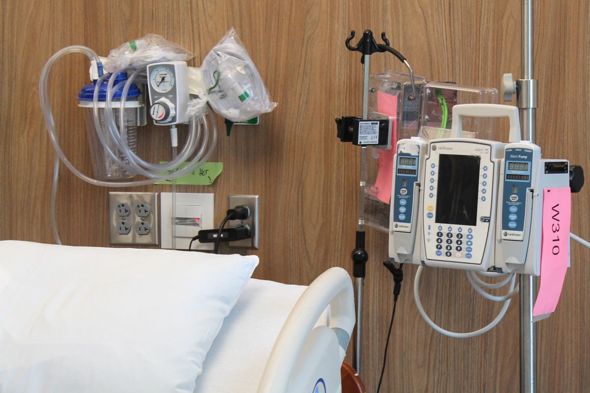 Medical equipment and machines sit next to a hospital bed in a hospital room. 