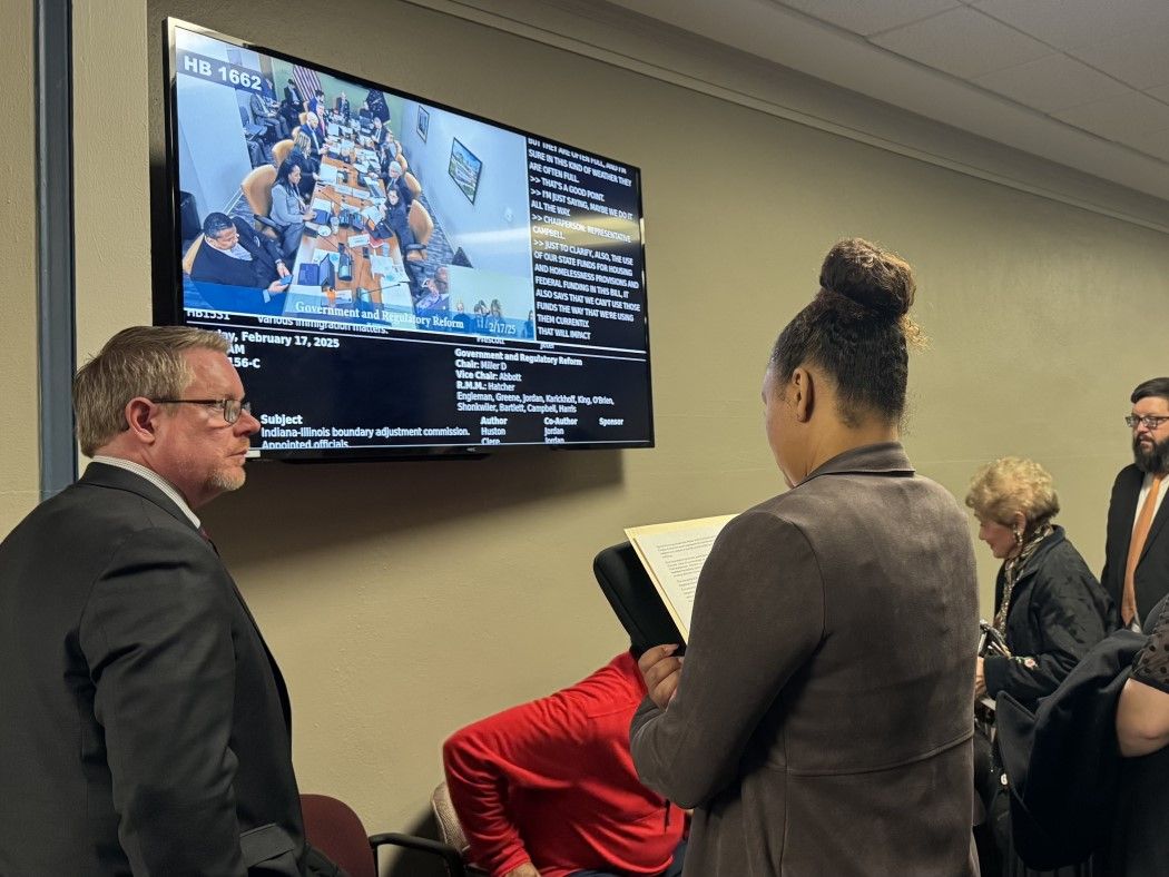 people standing watching a TV