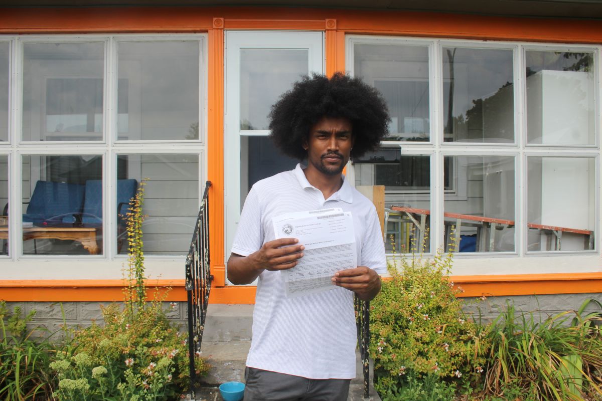 Mulugeta Wolfe holds up letters he’s received from the state about his Healthy Indiana Plan