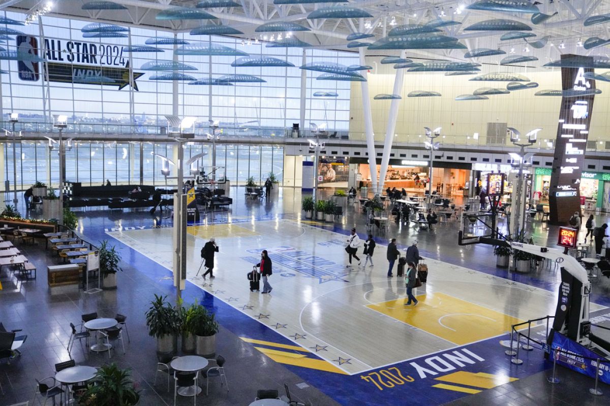 Travelers using Indianapolis International Airport make their way across a replica of the court that will be use for the NBA All-Star game Thursday, Jan. 18, 2024.