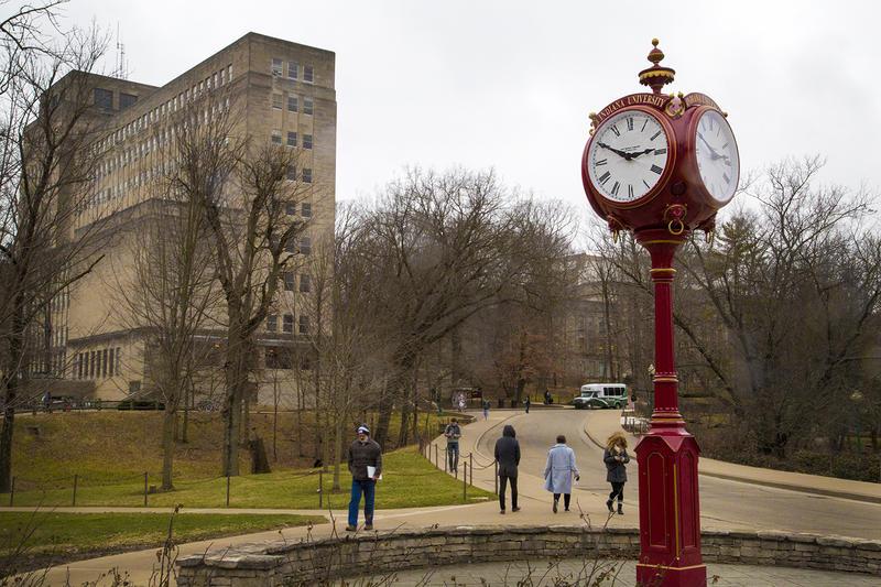 red clock stands next to IU building
