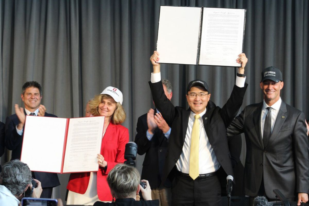 Purdue and Indiana University Presidents Mung Chiang and Pamela Whitten hold up the official agreement to dissolve IUPUI. 