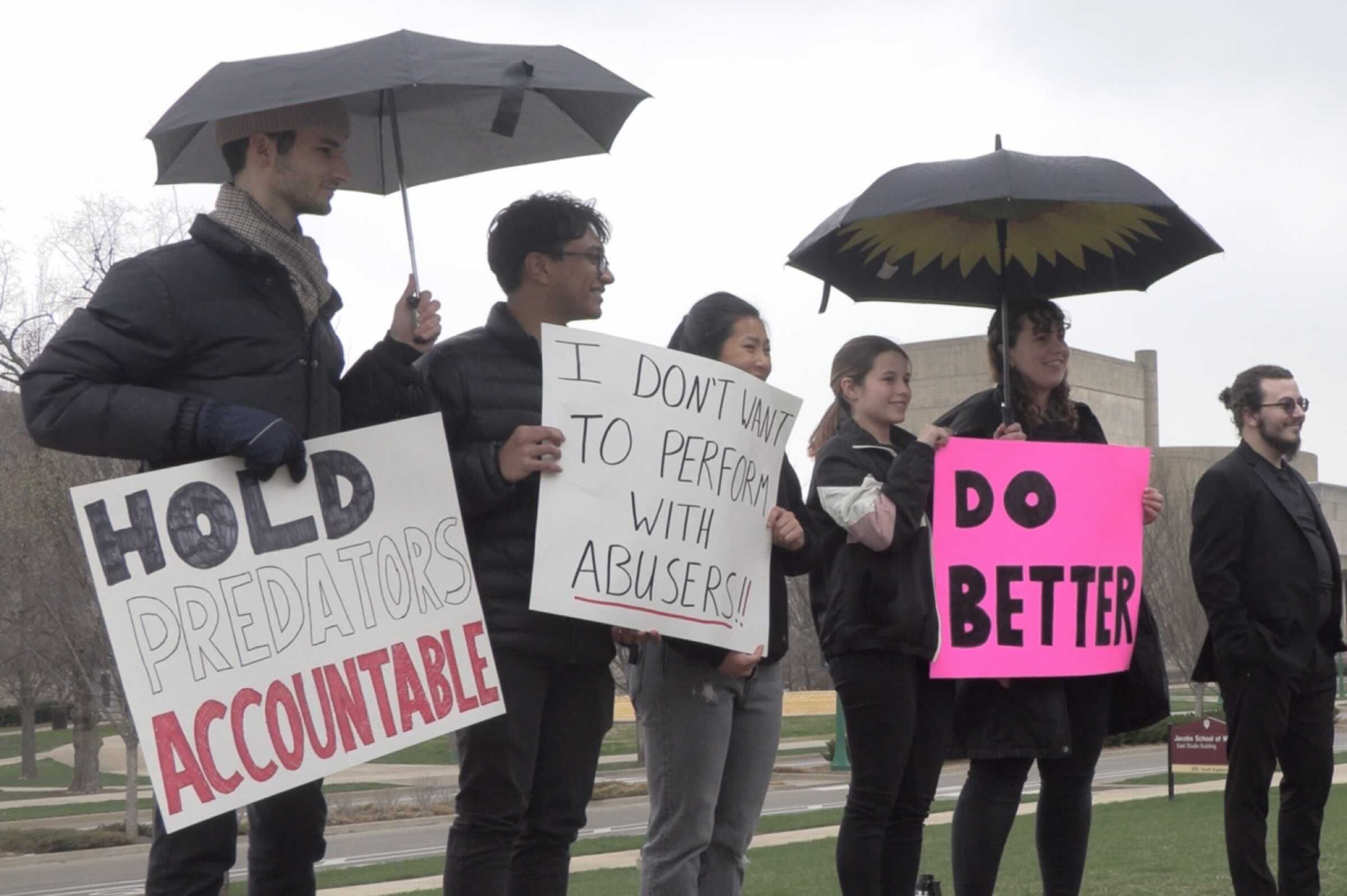 IU Jacobs School of Music students gather in front of the East Studio building in the rain to protest institutional apathy towards sexual violence 