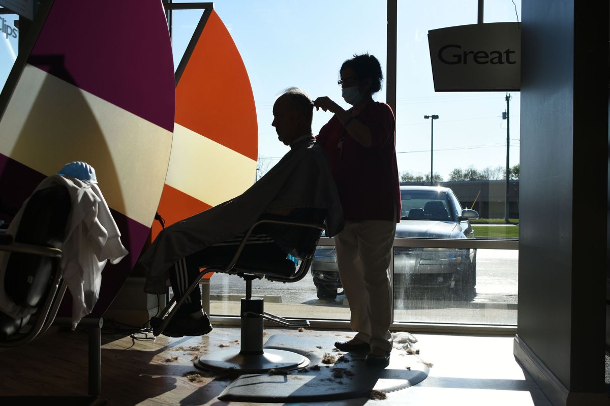 The silhouette of a barber cutting a man's hair.