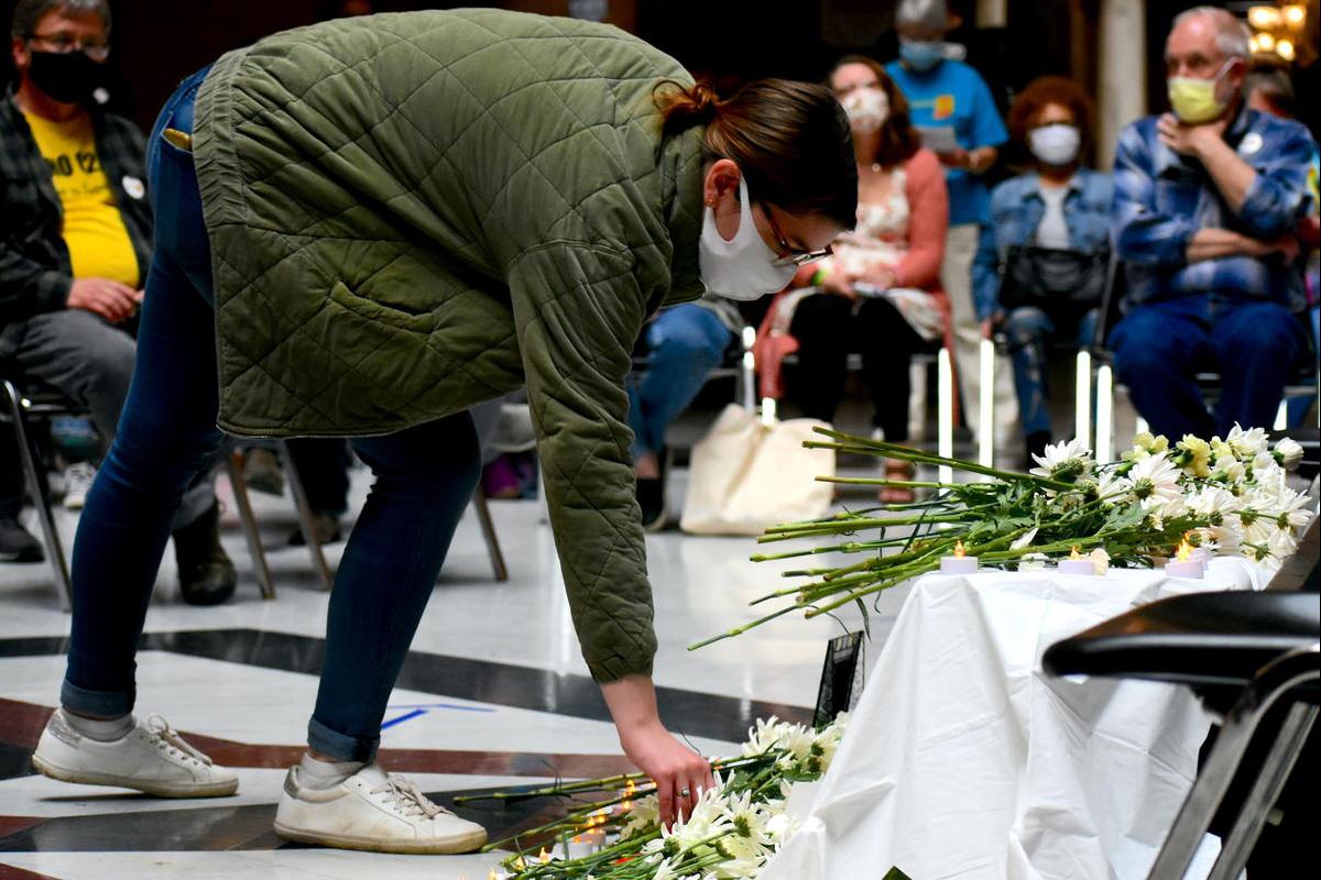 A person places a flower on a temporary memorial to commemorate Hoosiers who died as a result of a COVID-19 infection.