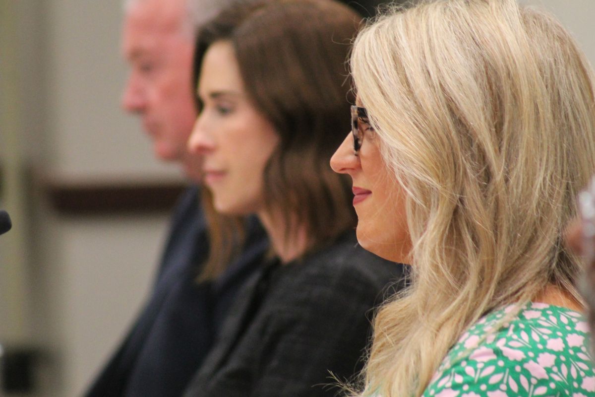 Indiana Secretary of Education Katie Jenner sits next to other State Board of Education board members during a meeting. Jenner has blonde hair and wears glasses. She is smiling at a speaker during a public feedback hearing.