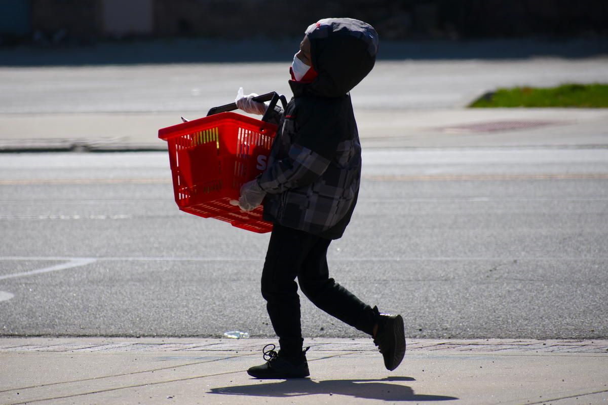 A child wearing a face mask and carrying a basket.