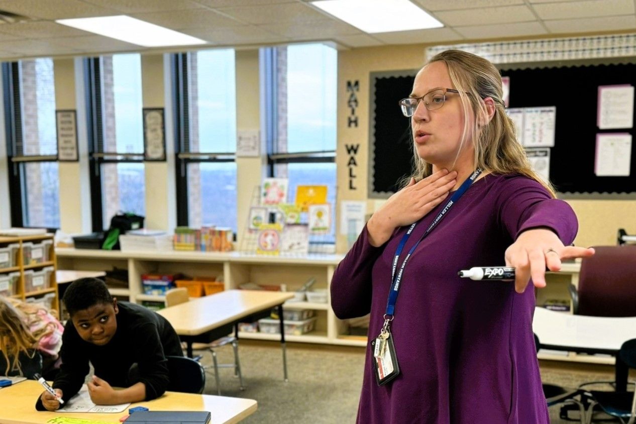 Second-grade teacher Morgan O'Dell holds her fingers to her throat to show her students how to feel whether they are using their vocal cords at Thomas Miller Elementary School in Lafayette on Tuesday, Dec. 4, 2023.
