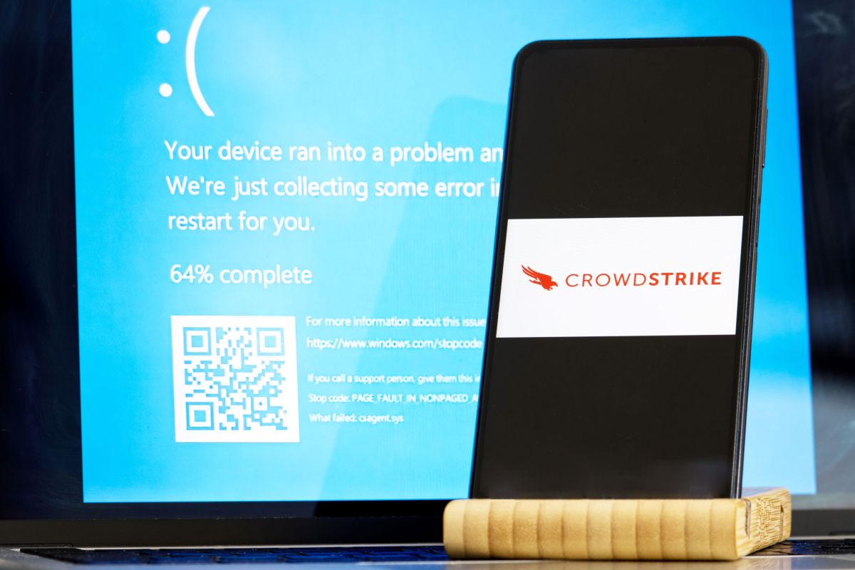 CrowdStrike logo and blue computer screen during mass tech outages worldwide have caused IT systems to shut down, Microsoft system error caused by CrowdStrike
