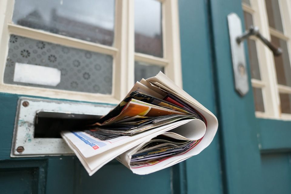 A generic photo of a newspaper and mail in a mail slot.