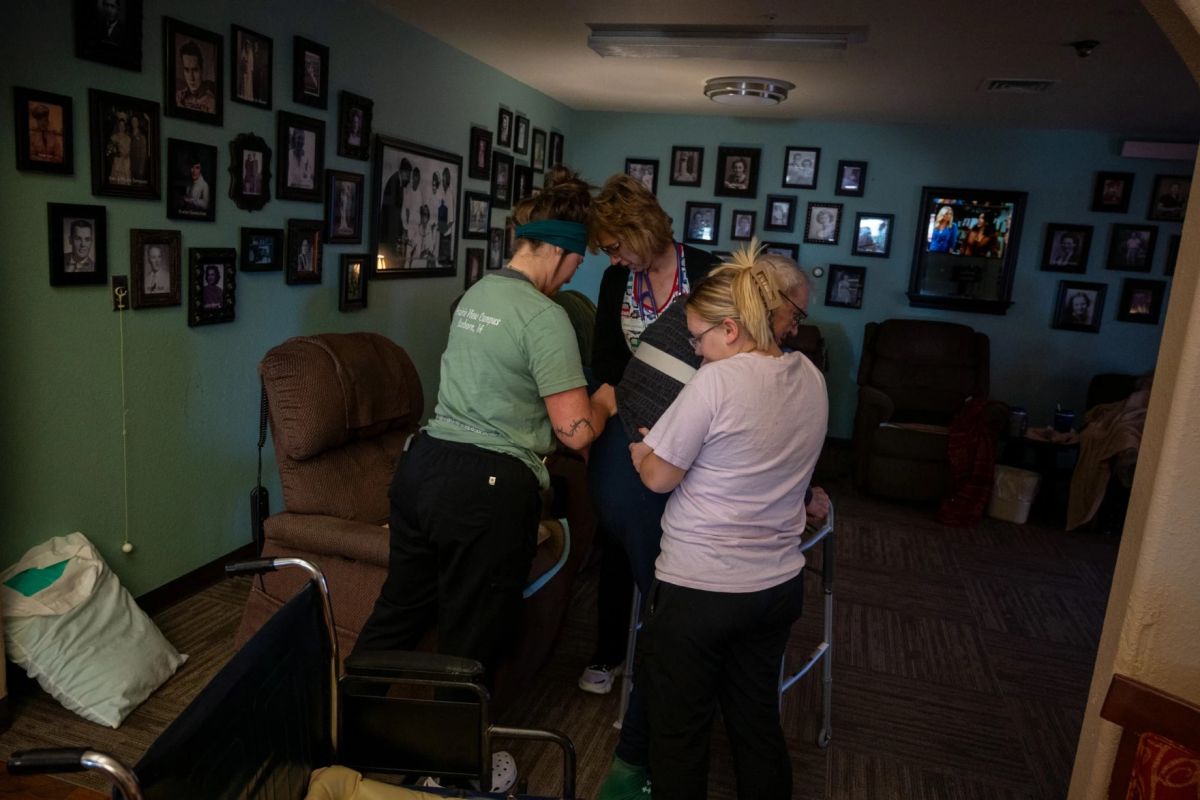 Employees at the Prairie View Nursing Home in Sanborn, Iowa, help a resident into a chair following lunch.