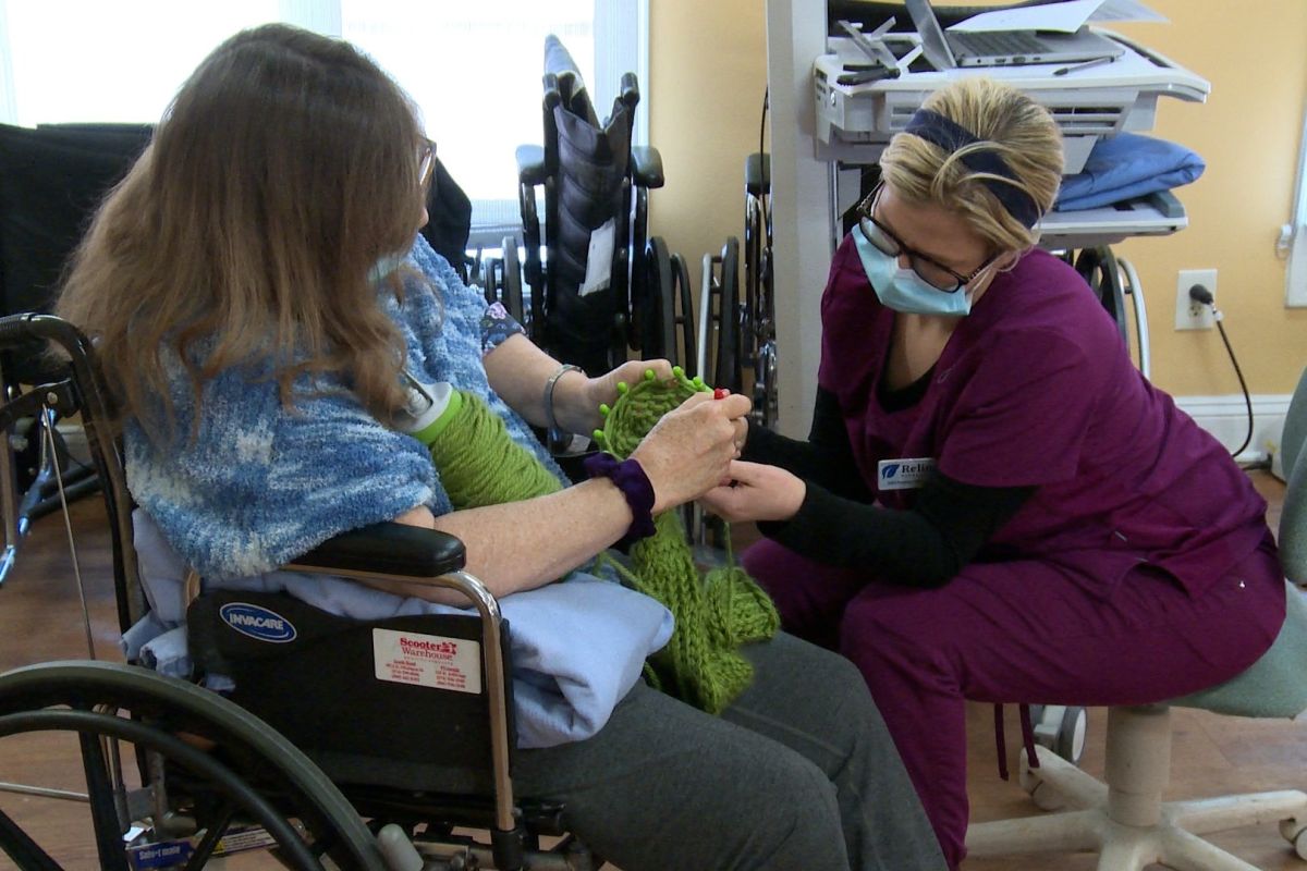 A worker at a South Bend nursing home helps a patient with a physical therapy activity.