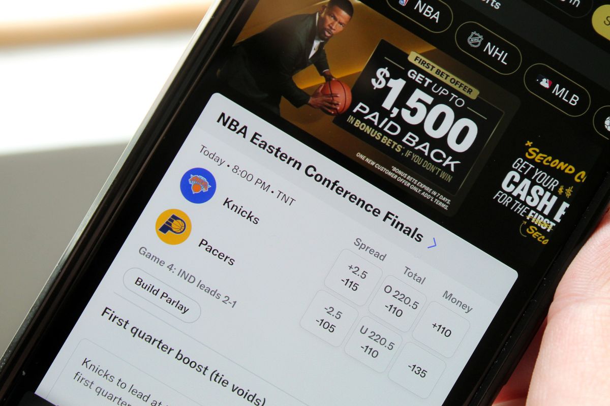 A phone screen shows a sports betting site.